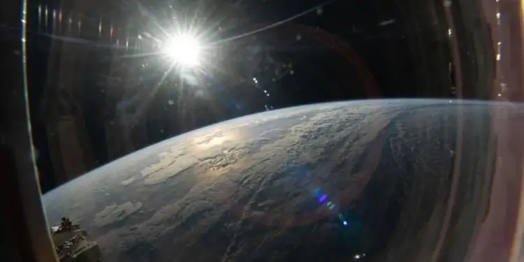 Vista panorámica de la curvatura de la Tierra con el sol brillando intensamente desde una escotilla espacial.