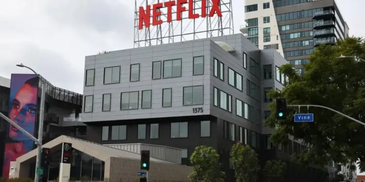Edificio corporativo con el logo de Netflix en rojo en la azotea. Fachada moderna con mural de rostro en un costado y señal de calle 'Vine'.