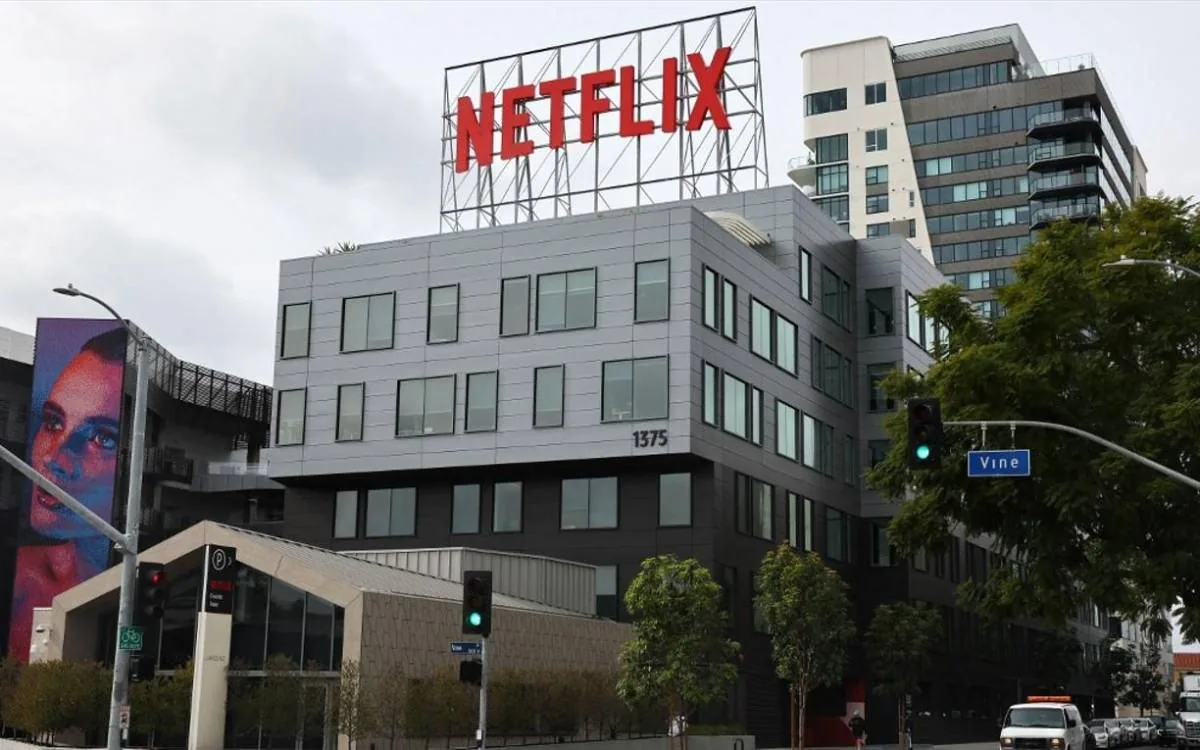 Edificio corporativo con el logo de Netflix en rojo en la azotea. Fachada moderna con mural de rostro en un costado y señal de calle 'Vine'.