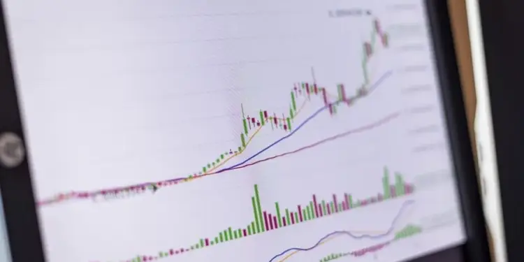 Pantalla de computadora mostrando una gráfica financiera con velas japonesas verdes y rojas y volumen de transacciones.