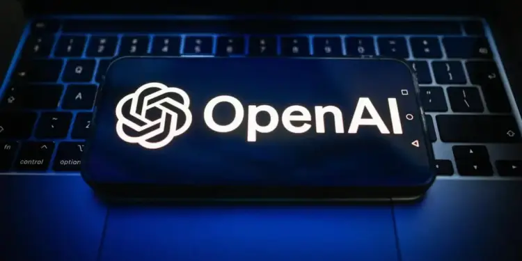 Logotipo de OpenAI y su nombre en pantalla de un smartphone colocado sobre el teclado de un portátil, simbolizando la integración de la inteligencia artificial en el mundo empresarial.