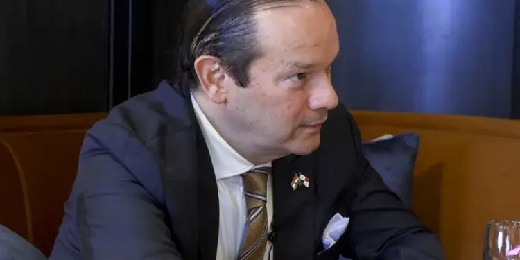 Hombre de negocios con traje oscuro y corbata a rayas sentado en una mesa