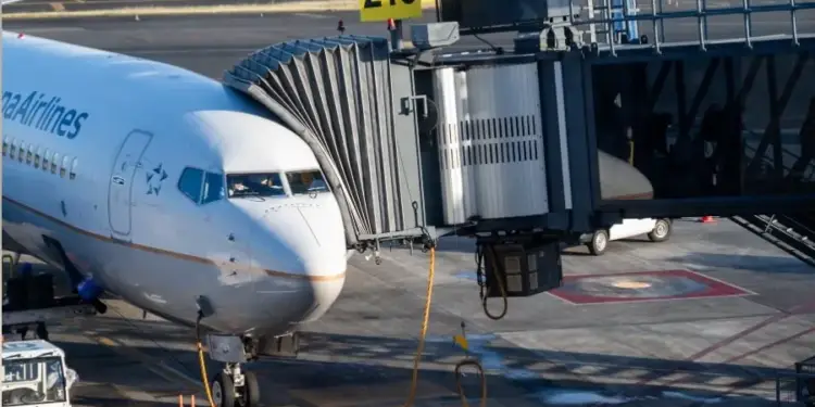 Vista frontal de un avión comercial conectado a la pasarela de acceso en la pista del aeropuerto.