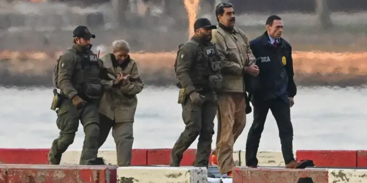 Un grupo de agentes tácticos escoltando a varias personas esposadas en un muelle.
