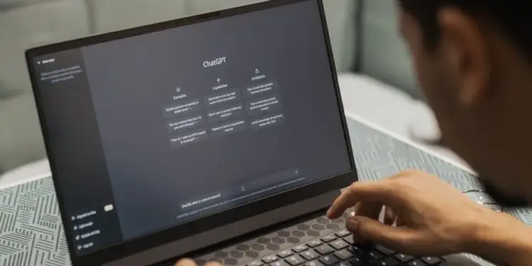 Persona escribiendo en el teclado de una laptop con la interfaz de ChatGPT abierta en la pantalla.