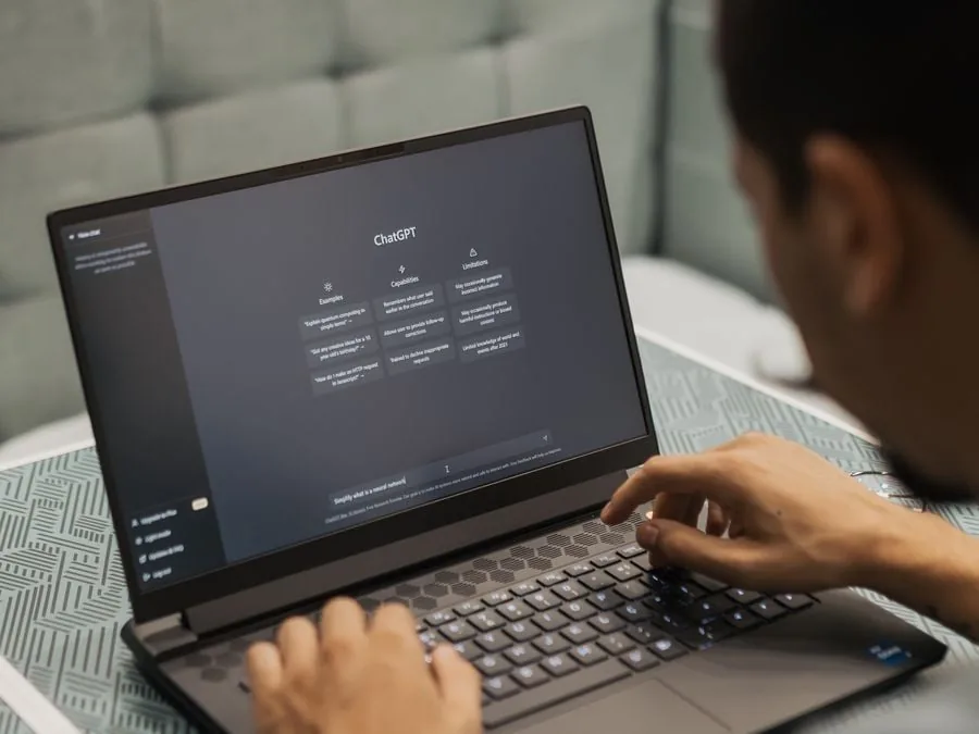 Persona escribiendo en el teclado de una laptop con la interfaz de ChatGPT abierta en la pantalla.