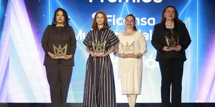 Cuatro mujeres posan en un escenario con premios en forma de corona dorada, celebrando logros empresariales y profesionales.