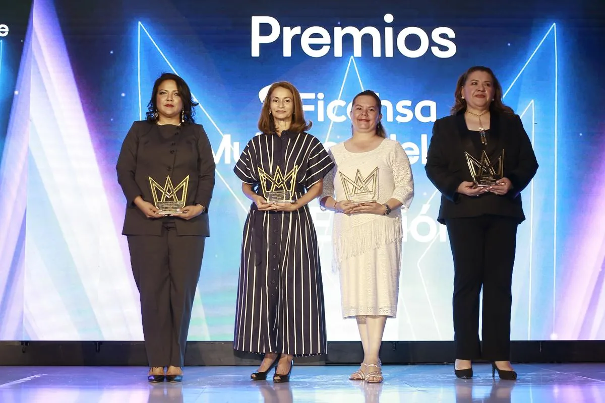 Cuatro mujeres posan en un escenario con premios en forma de corona dorada, celebrando logros empresariales y profesionales.