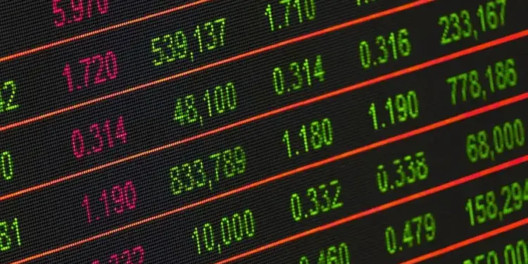 Primer plano de una pantalla digital mostrando filas de números financieros en rojo y verde, representando datos del mercado bursátil.
