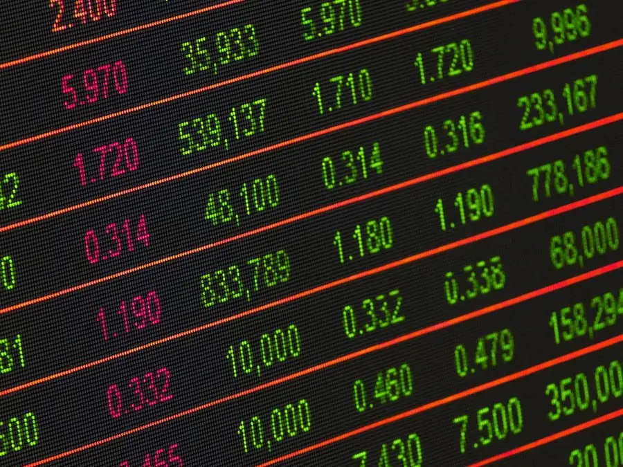 Primer plano de una pantalla digital mostrando filas de números financieros en rojo y verde, representando datos del mercado bursátil.