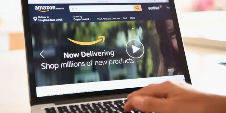 Persona usando un portátil para navegar por la página web de Amazon.com.au, mostrando la opción de entrega y la búsqueda de productos.