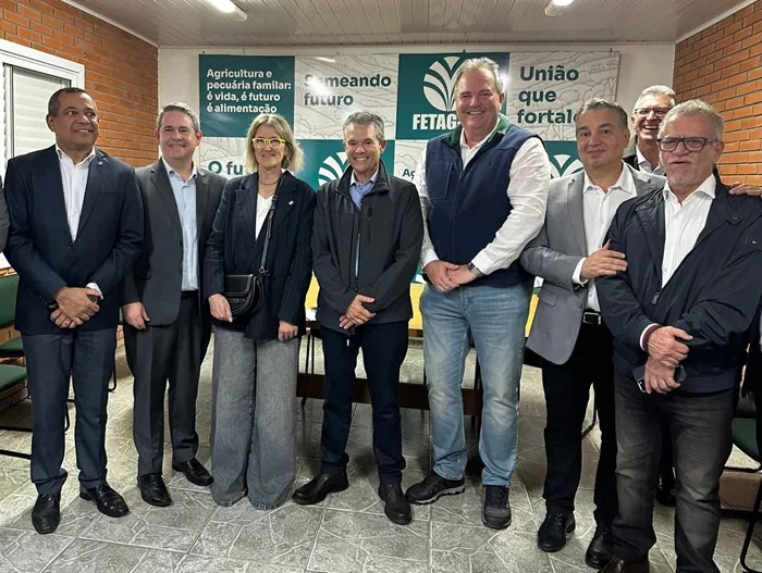 Grupo de hombres y una mujer de negocios posando juntos en una sala de reuniones con paneles informativos al fondo.
