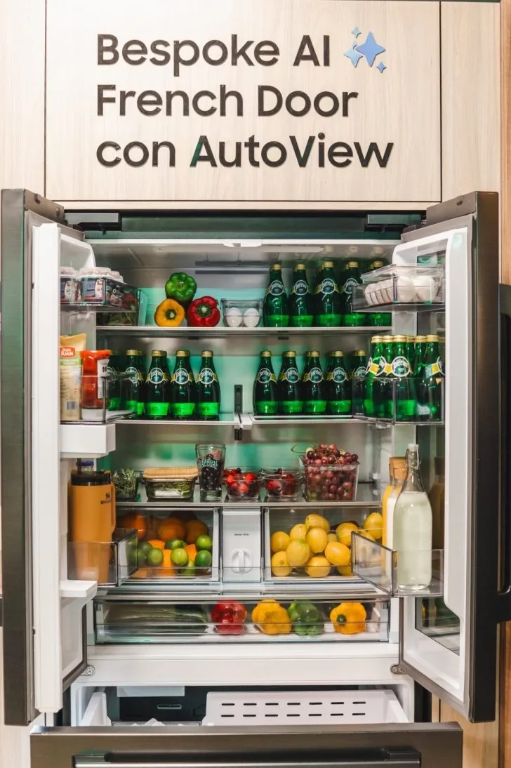 Refrigerador moderno con puertas francesas abiertas mostrando estantes organizados llenos de bebidas y alimentos frescos.