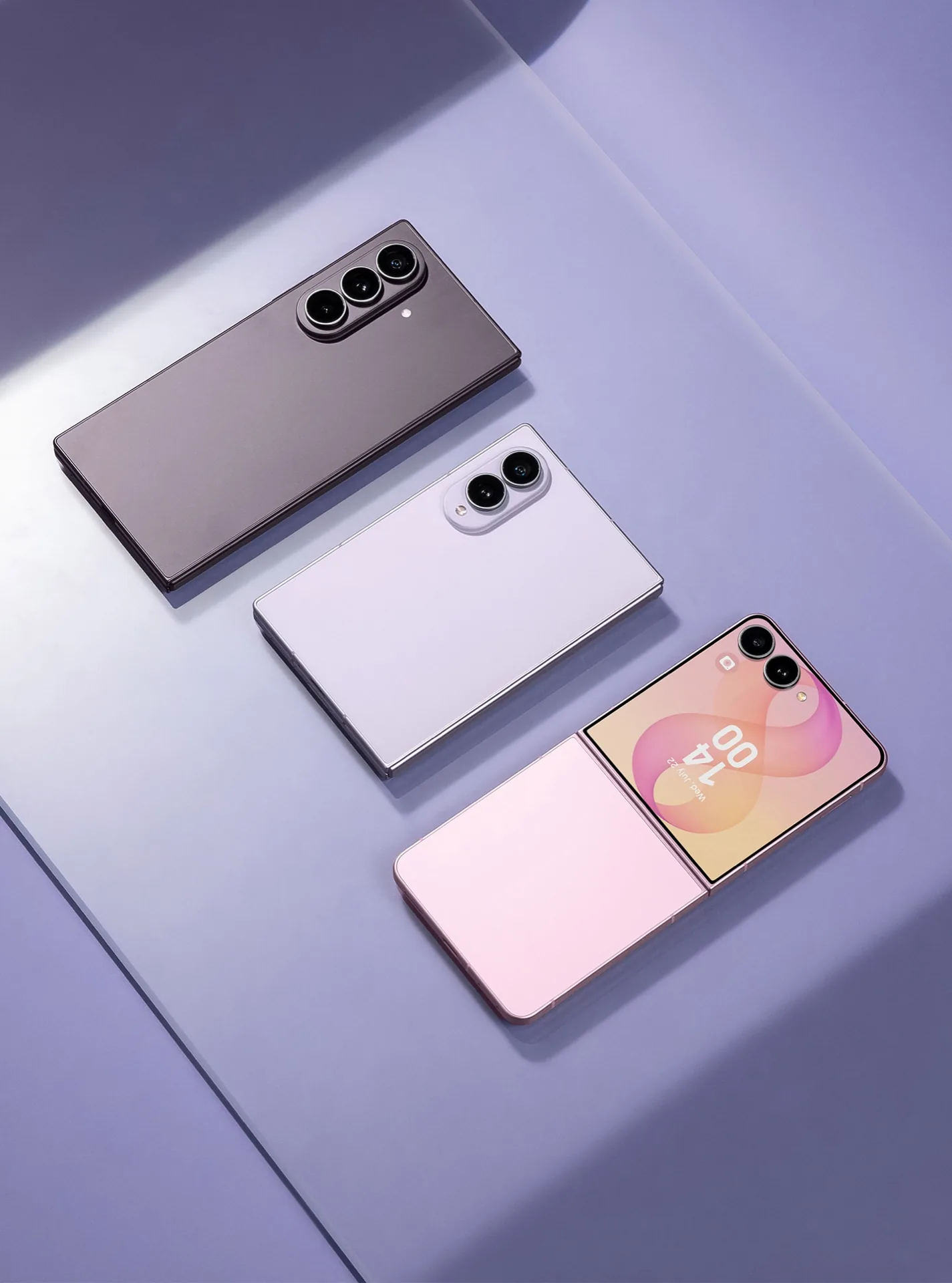 Tres teléfonos inteligentes modernos de diseño plegable y rectangular colocados en diagonal sobre una superficie violeta.