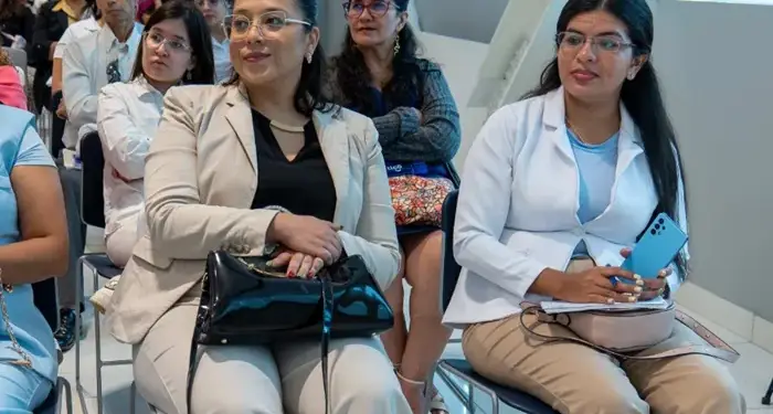Grupo de profesionales sentados escuchando una conferencia de negocios en una sala iluminada.