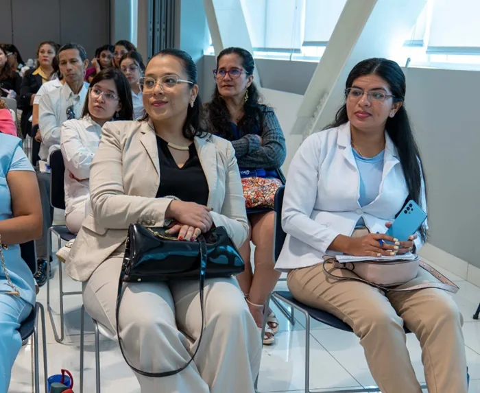 Grupo de profesionales sentados escuchando una conferencia de negocios en una sala iluminada.