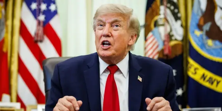Donald Trump hablando frente a banderas estadounidenses en un despacho oficial.