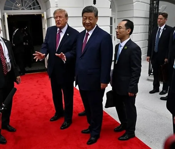 Dos líderes políticos con traje y corbata caminando sobre una alfombra roja junto a otros oficiales.