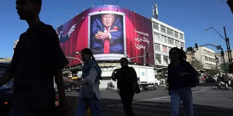 Gran cartel publicitario en esquina de edificio con caricatura de figura política en traje, sosteniendo objetos. Peatones cruzan calle.