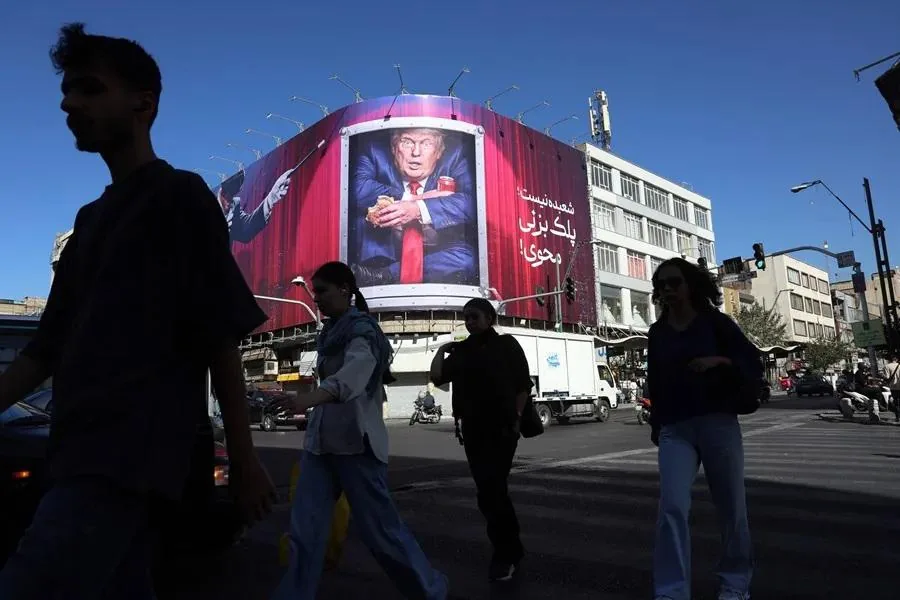 Gran cartel publicitario en esquina de edificio con caricatura de figura política en traje, sosteniendo objetos. Peatones cruzan calle.