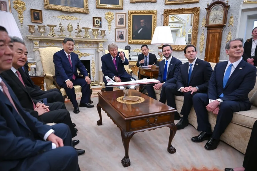 Grupo de hombres en traje reunidos en una lujosa sala con un modelo de avión sobre la mesa de centro