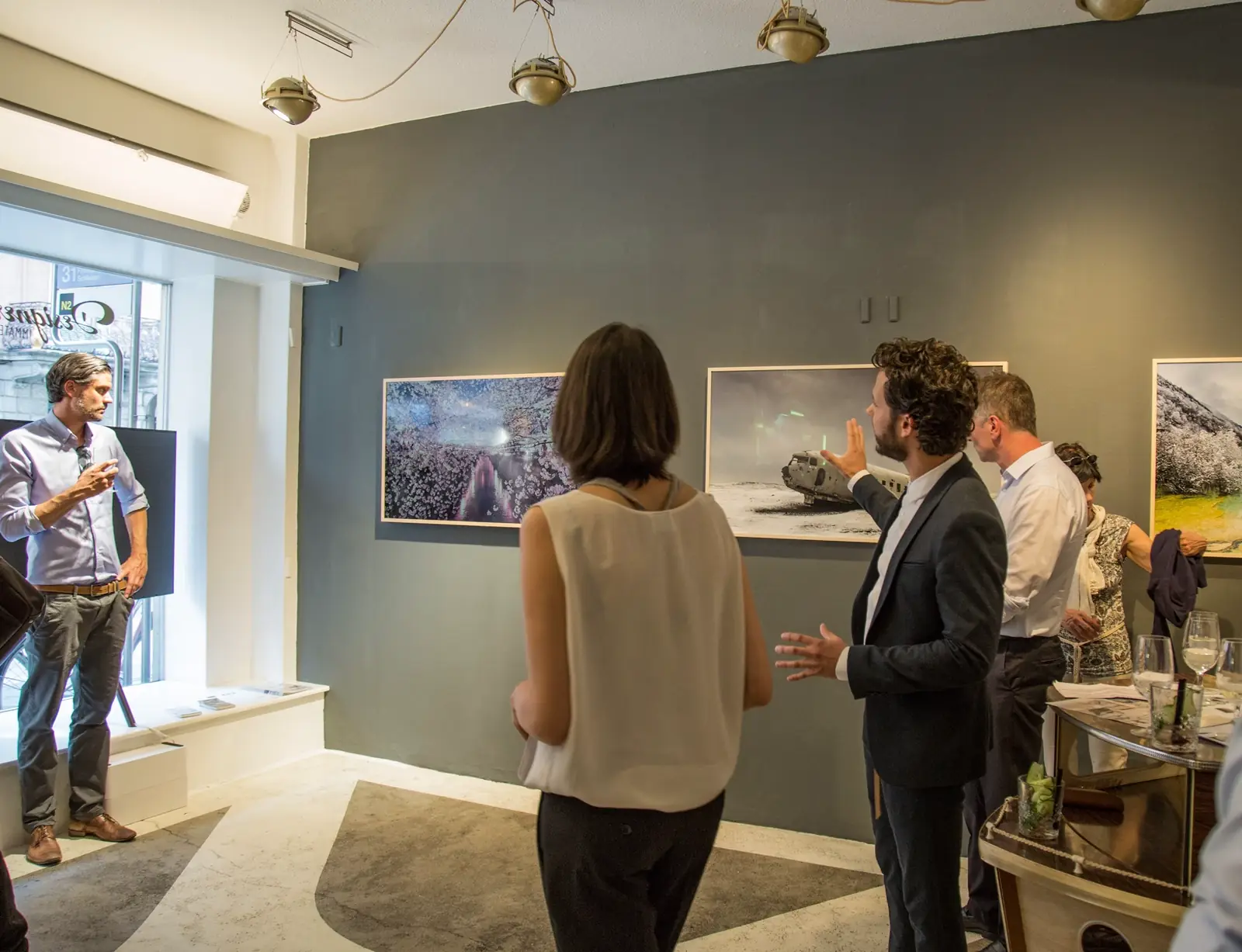 Grupo de profesionales observando y discutiendo sobre obras de arte en una galería con paredes oscuras.