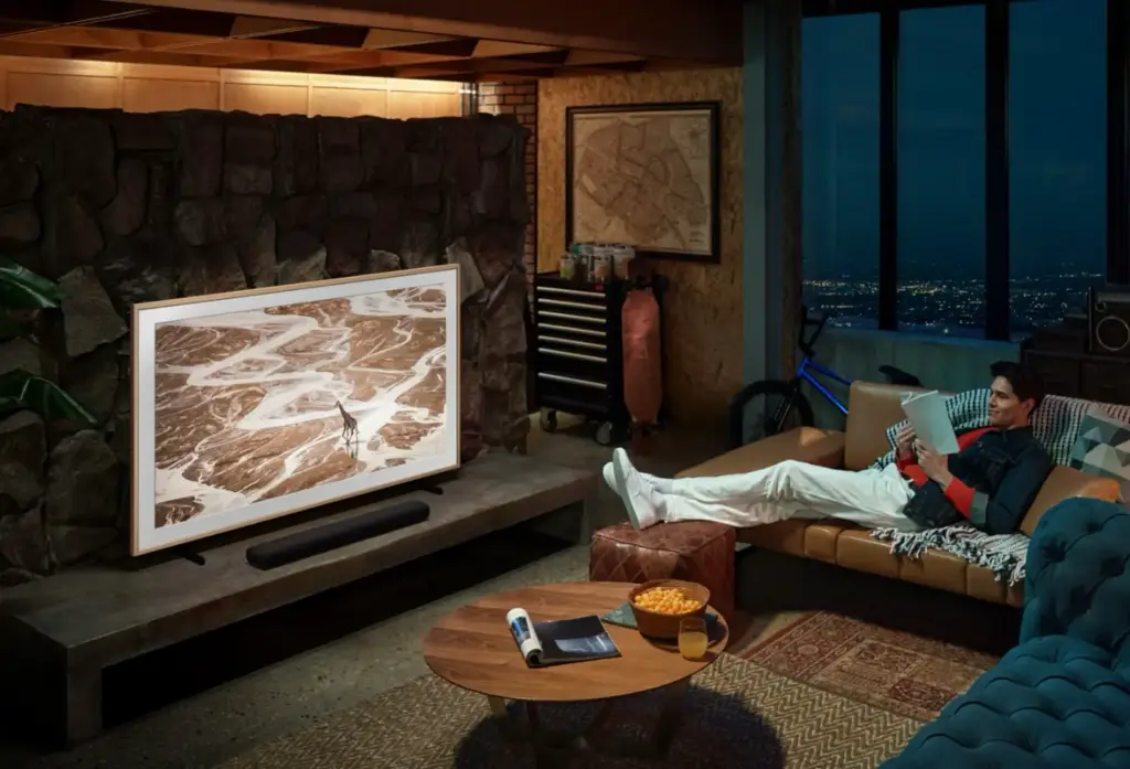 Hombre relajado leyendo un libro en un sofá de diseño en un amplio salón moderno con televisión integrada.