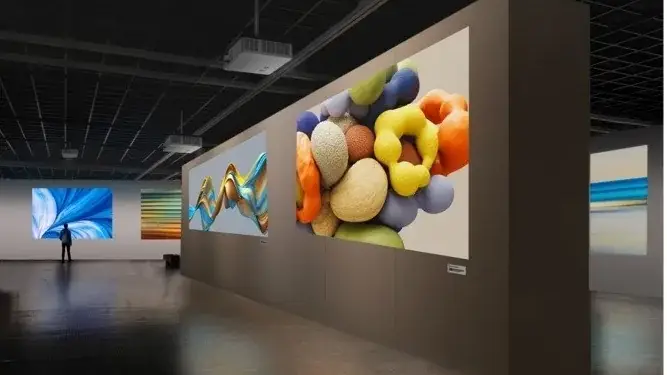 Vista interior de una galería de arte moderna con grandes pantallas que muestran obras abstractas coloridas.