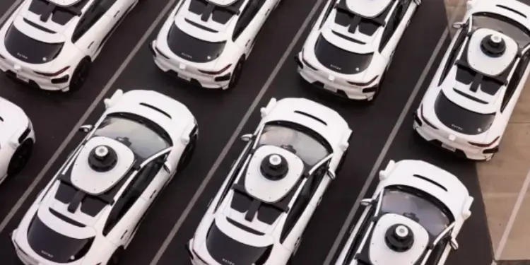 Vista aérea de varios automóviles blancos con equipos de sensores en el techo estacionados ordenadamente.