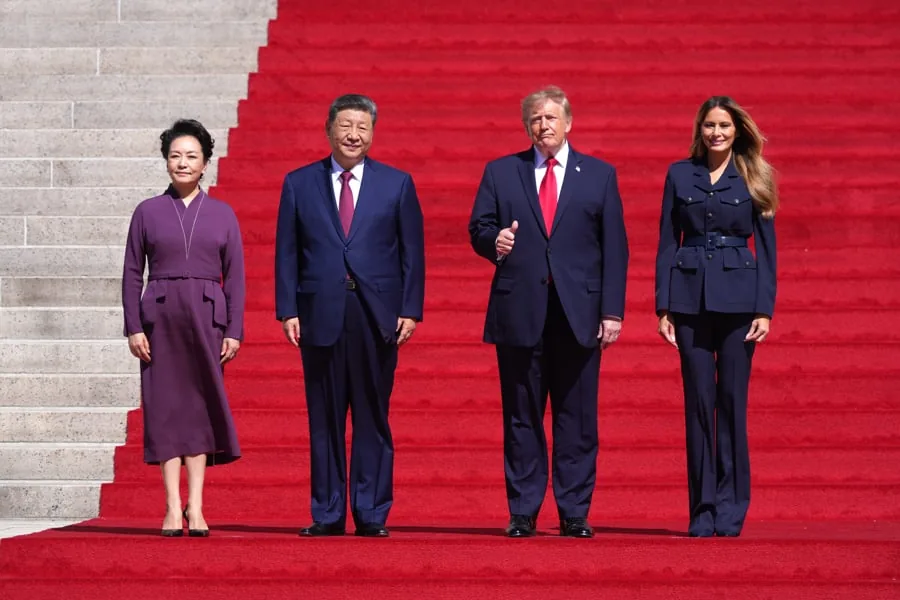 Cuatro personas de pie sobre una alfombra roja en una escalinata monumental durante una visita diplomática oficial.