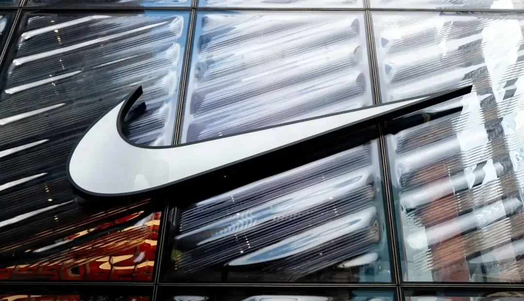 Logotipo corporativo de Nike en color blanco sobre una fachada de paneles de vidrio estructurado.