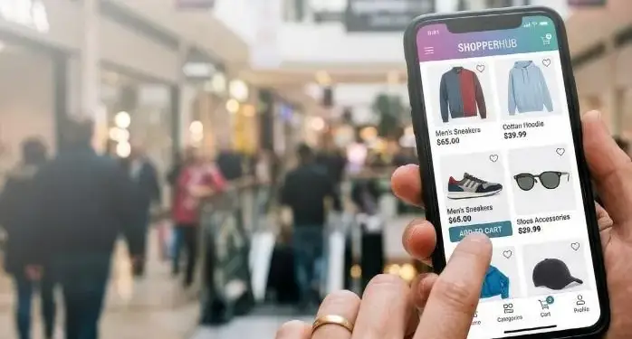 Persona utilizando una aplicación de comercio electrónico en su teléfono móvil dentro de un centro comercial.
