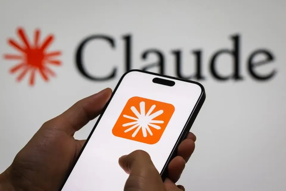 Manos sosteniendo un smartphone que muestra el logotipo de la aplicación Claude con fondo de pantalla con marca.