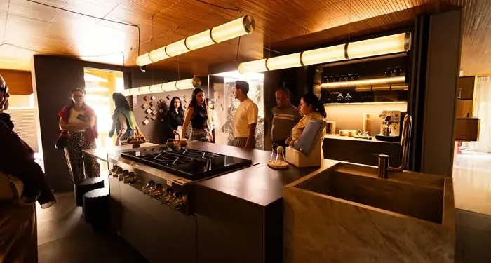Grupo de personas reunidas en una cocina moderna durante un evento de negocios o presentación profesional.