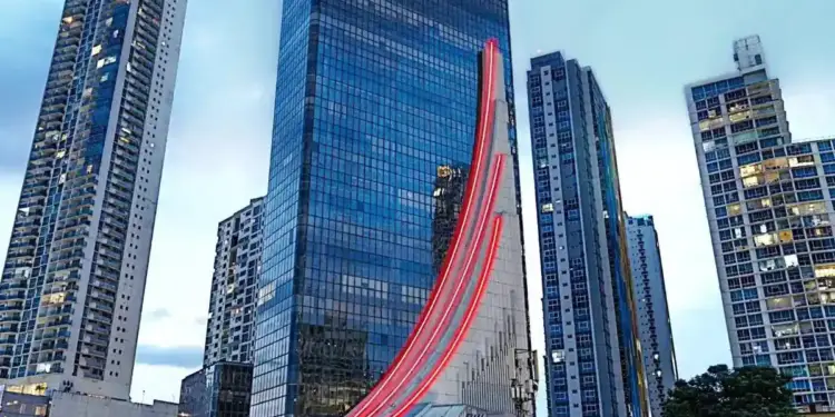 Vista exterior de un moderno rascacielos con fachada de vidrio y el logotipo iluminado de BAC en la parte superior.