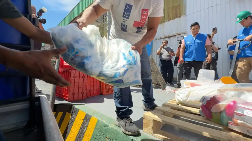 Hombres entregando bolsas con productos y mercancía en una zona de carga y distribución industrial.