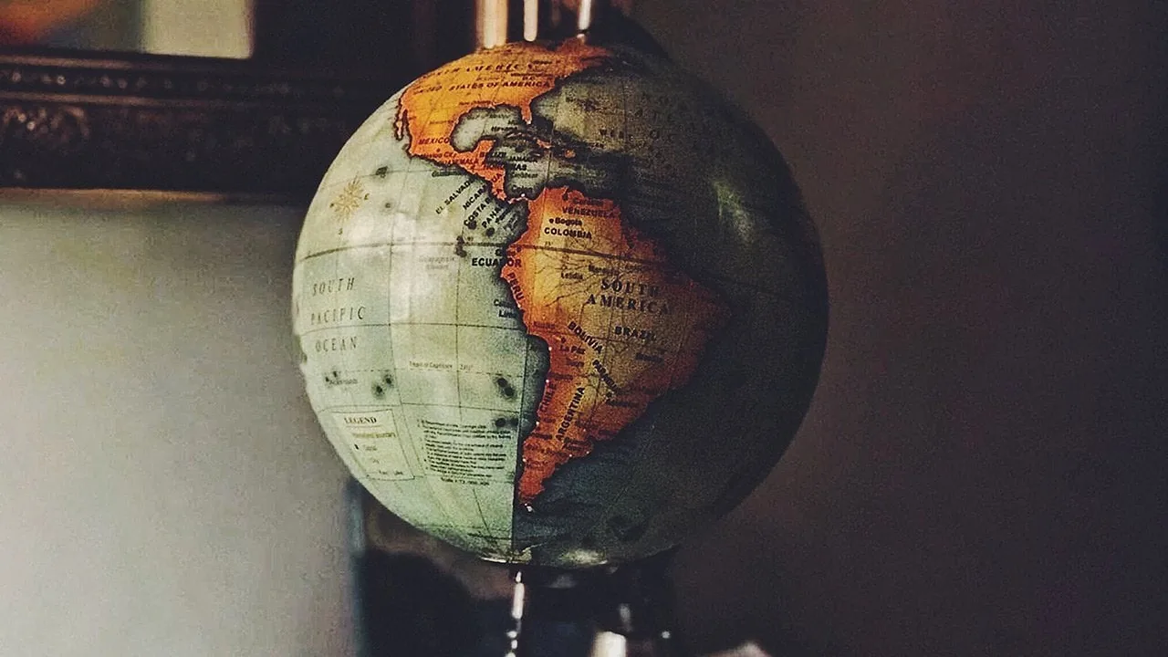 Globo terráqueo antiguo enfocado en el continente americano y el océano Pacífico con tonos oscuros.