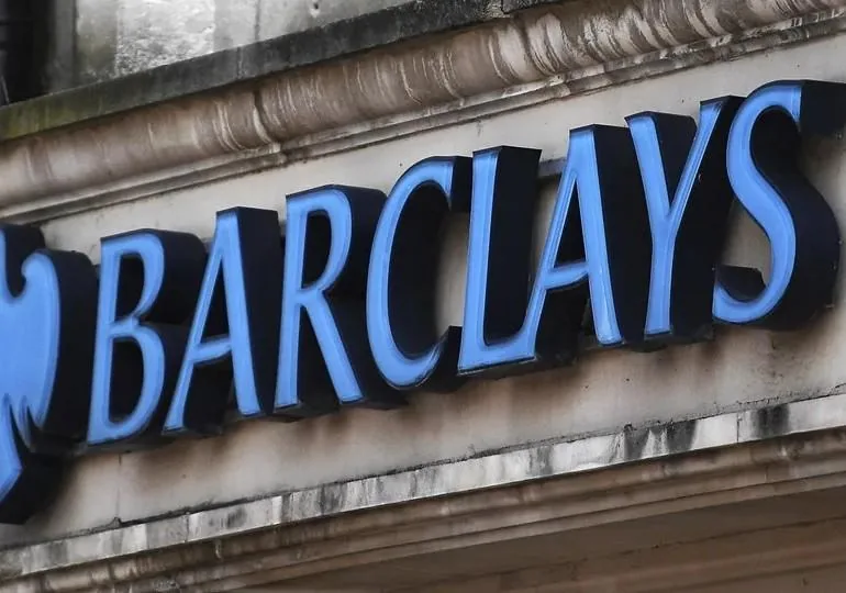 Letrero con letras tridimensionales azules del banco Barclays sobre la fachada de piedra de una sucursal bancaria.