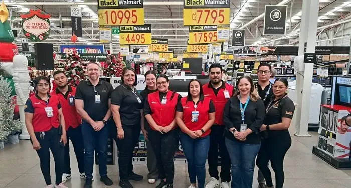 Grupo de empleados de pie en el interior de un gran establecimiento comercial con carteles de precios.