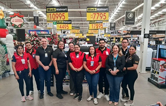 Grupo de empleados de pie en el interior de un gran establecimiento comercial con carteles de precios.