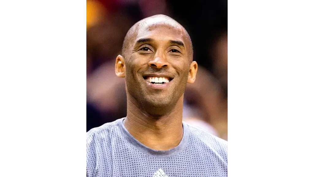 Retrato de primer plano de Kobe Bryant sonriendo con una camiseta gris texturizada.