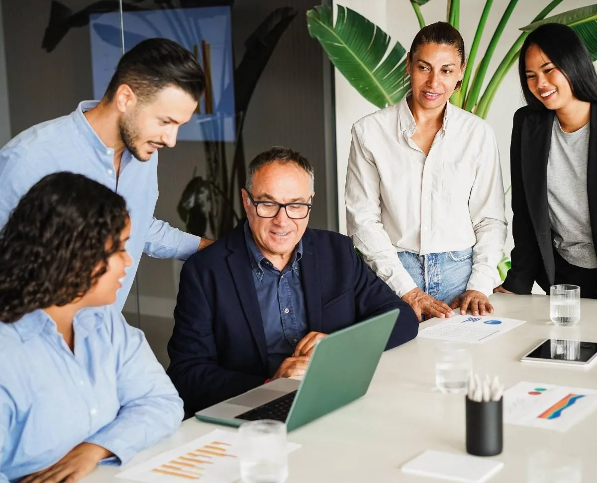 Grupo diverso de profesionales reunidos alrededor de una mesa colaborando en una oficina.