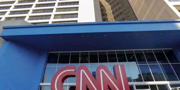 Fachada de un edificio corporativo moderno con el logotipo rojo de CNN en la entrada principal y personas caminando.
