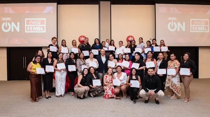 Amplio grupo de mujeres y algunos hombres posando con diplomas en un evento corporativo de Coca-Cola FEMSA.
