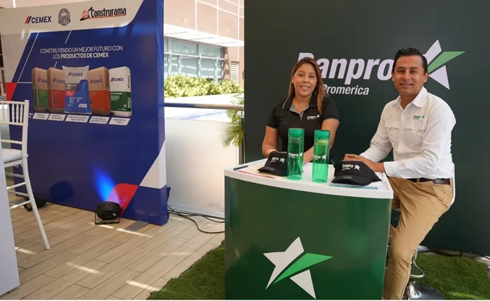 Dos personas sonriendo junto a un mostrador corporativo con logotipos de Banpro Promerica y Cemex en un evento