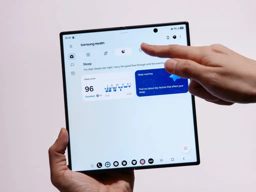 Manos sostienen un Galaxy Z Fold8 abierto con Samsung Health mostrando una puntuación de sueño de 96 y la tarjeta de Sleep Coaching