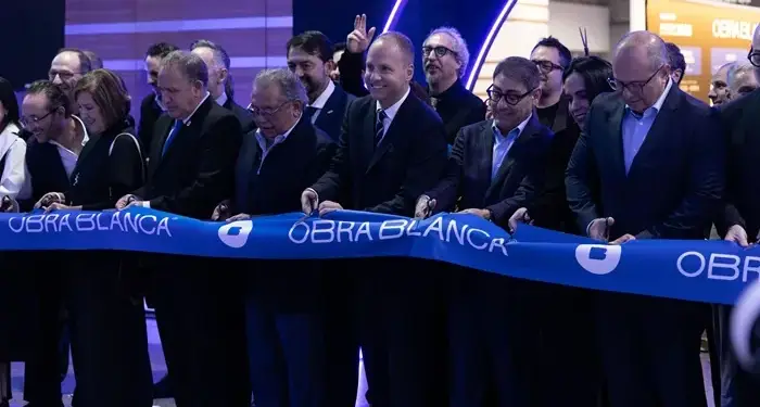 Grupo de profesionales y empresarios cortando un listón azul inaugural en un evento corporativo.