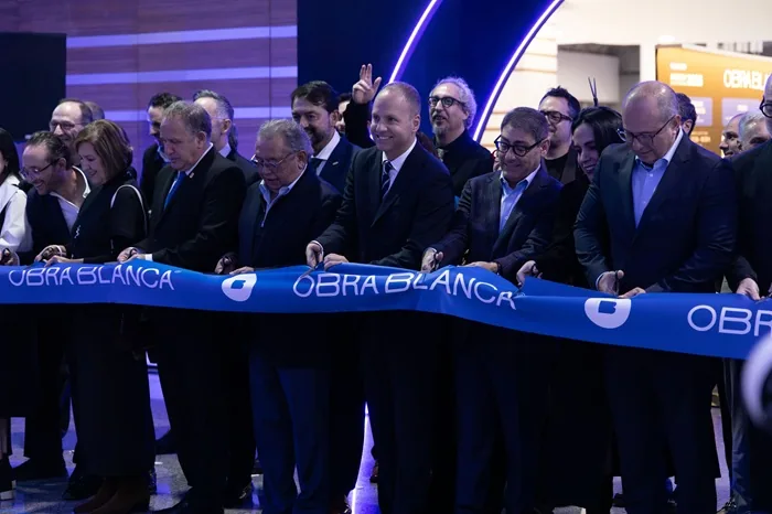Grupo de profesionales y empresarios cortando un listón azul inaugural en un evento corporativo.
