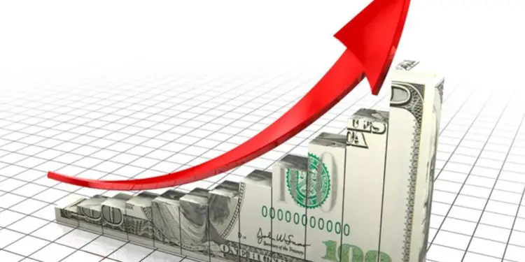Gráfico de barras ascendente con textura de billetes de cien dólares y una flecha roja curva hacia arriba.