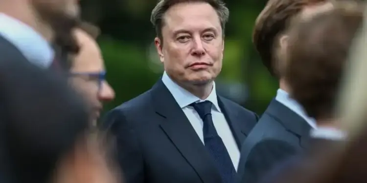 Retrato de Elon Musk vistiendo traje formal y corbata oscura en un evento empresarial.